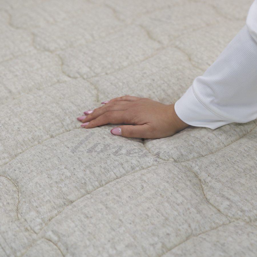 Detail lněného potahu LINEN matrace BIOGREEN LINE T4 s rukou na jeho povrchu.