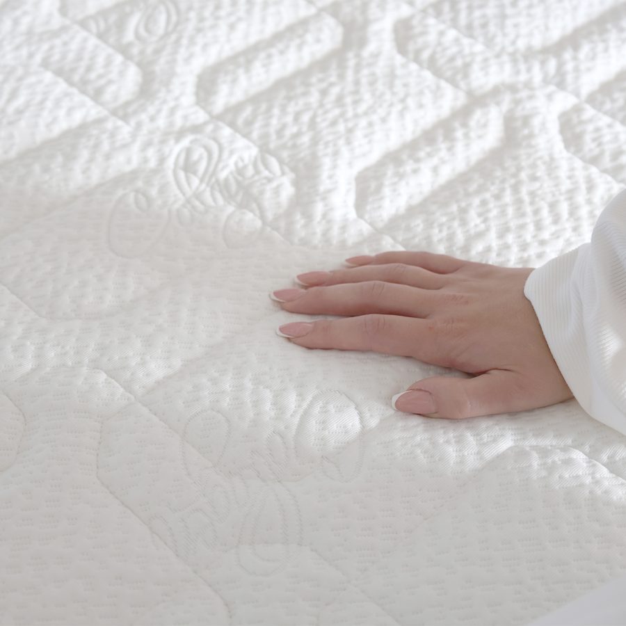 Matrace OXYGEN HYDROLATEX, detail bílého potahu COLLAGEN s rukou na prošívaném povrchu.