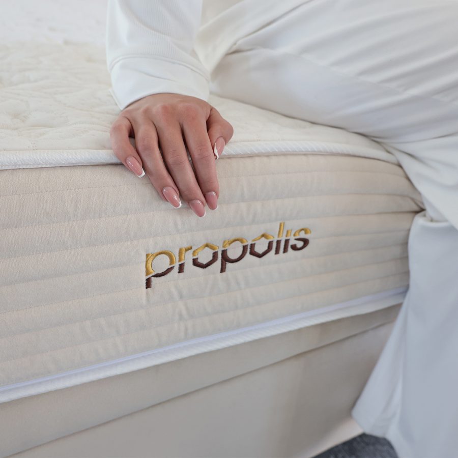 Matrace PROPOLIS COMFORT, detail bočního potahu s logem PROPOLIS při dotyku ruky.